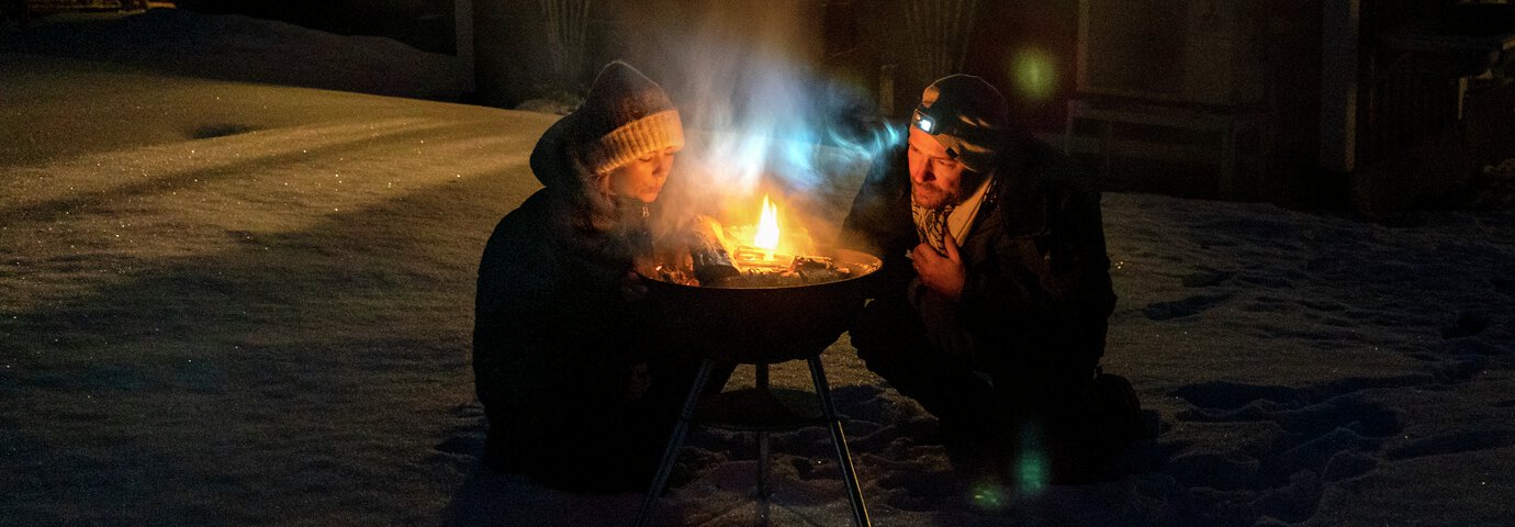 hemberedskap - två personer blåser på en eld i eldfat